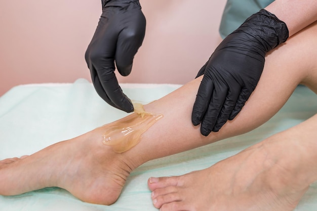 Épilation au studio spa. Cire de jambes de femme avec sucrage. Sucre chaud.