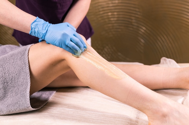 Épilation à la boutique de luxe spa. Cire de jambes de femmes avec sucre. Sucre chaud.