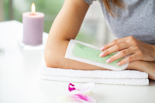 Épilation de processus mains féminines dans un salon de beauté