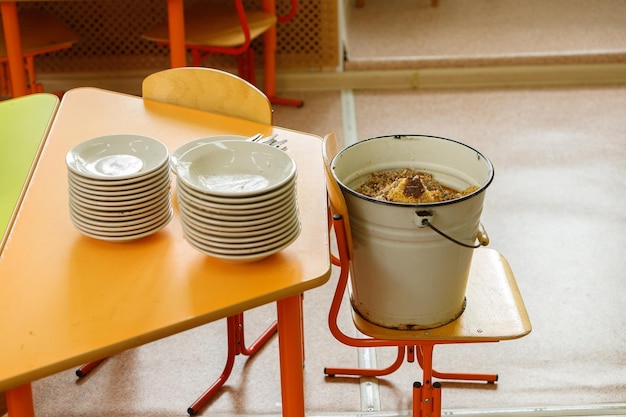 Une pile d'assiettes sur la table à côté d'un seau en métal rempli de nourriture