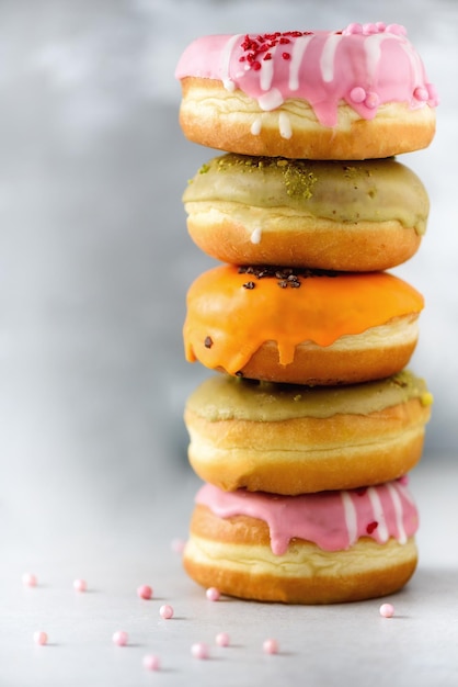 Pile de beignets assortis colorés glacés avec arrose sur fond de ciment gris Espace de copie Beignets sucrés pour les enfants