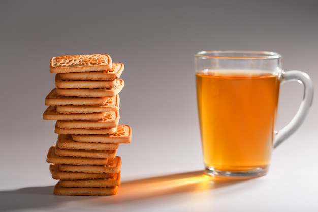 Une pile de biscuits au blé doré et une tasse de thé vert parfumé sur fond gris