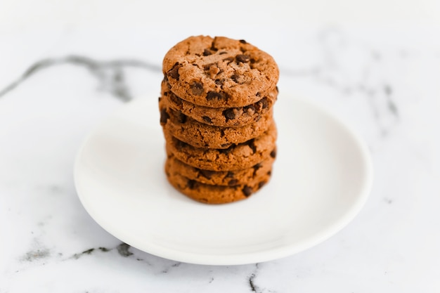 Pile de biscuits au chocolat au four sur une plaque blanche sur le fond de marbre