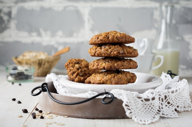 Pile de biscuits à l'avoine avec du chocolat sur une lumière avec des flocons et une bouteille de lait.