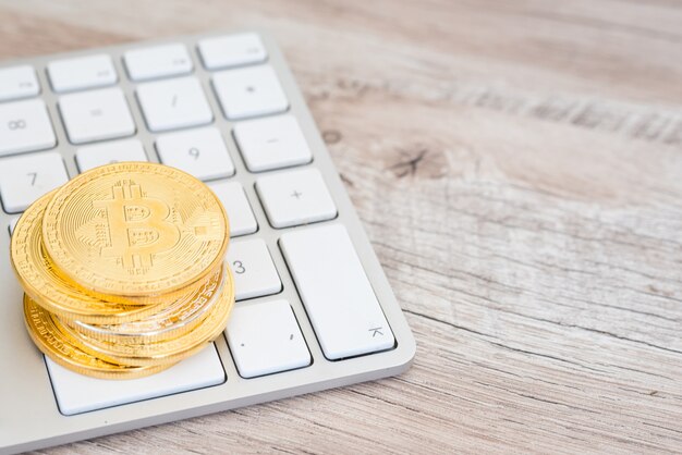 Pile de bitcoins d'or sur un clavier blanc