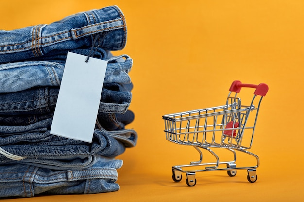 Une pile de blue-jeans avec une étiquette vierge blanche sur un backgroundhopping trolley Sales consept tas de pantalons en denim à la mode élégant