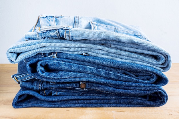 Pile de blue jeans sur une table en bois.