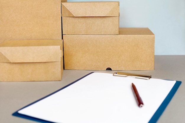 une pile de boîtes en carton et un presse-papiers avec une feuille de papier sur une table grise