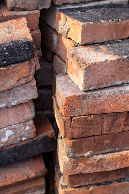 Une pile de briques réfractaires rouges non neuves pour la pose d'un poêle domestique.