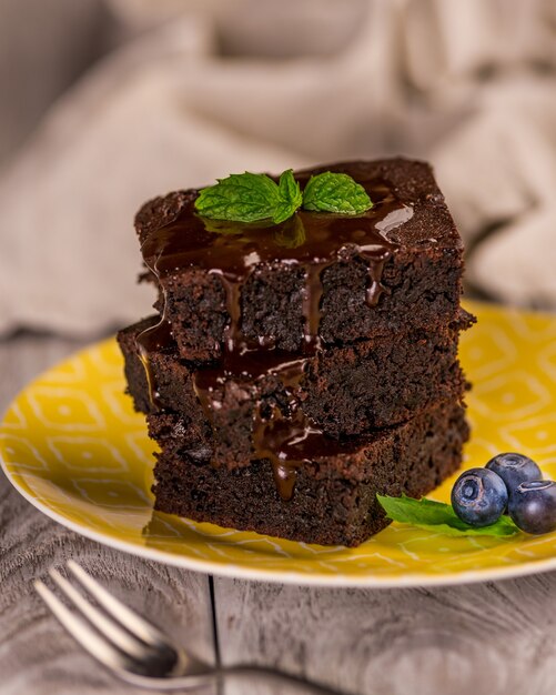 Une pile de brownies au chocolat sur une surface en bois avec feuille de menthe sur le dessus, boulangerie maison et dessert