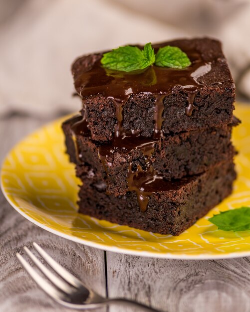 Une pile de brownies au chocolat sur table en bois avec feuille de menthe sur le dessus, boulangerie maison et dessert.