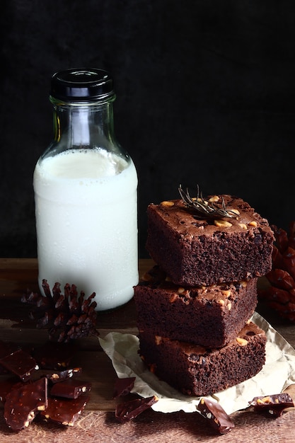 Pile de brownies sur fond de table en bois marron foncé Il y a des bouteilles de lait et des chocolats