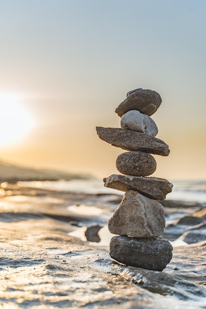 Une pile de cailloux sur la plage contre un ciel clair au coucher du soleil
