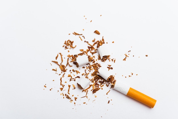 Pile cassée de cigarettes ou de tabac sur fond blanc