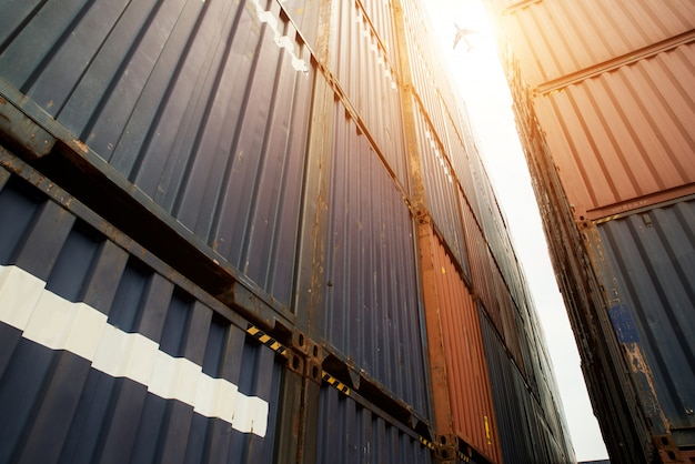 Pile de conteneurs de fret à la zone d&#39;importation et d&#39;exportation avec avion cargo au port.