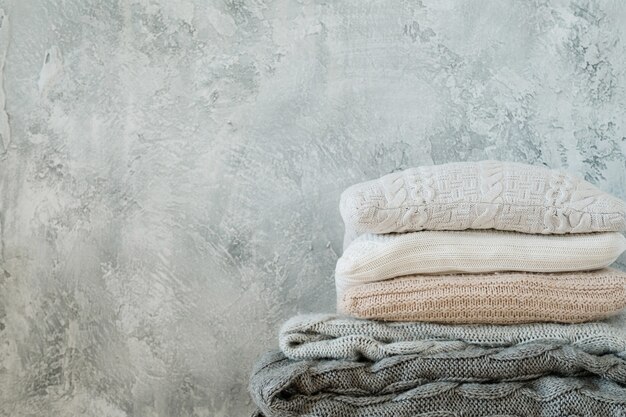 Pile de couvertures et plaids tricotés sur fond gris minable. décor à la maison chaleureux et confortable