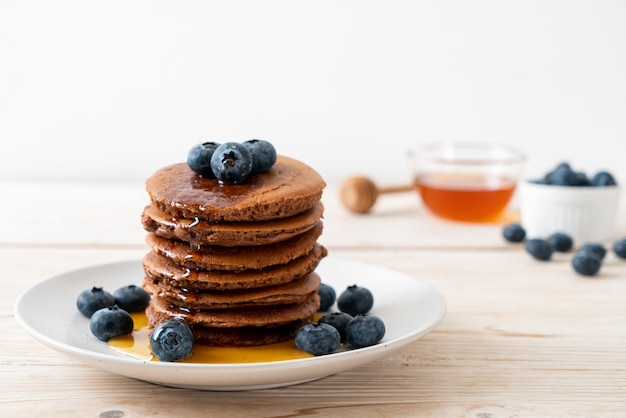 Pile de crêpes au chocolat aux myrtilles et miel sur assiette