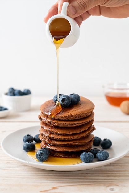 Pile de crêpes au chocolat aux myrtilles et miel sur assiette