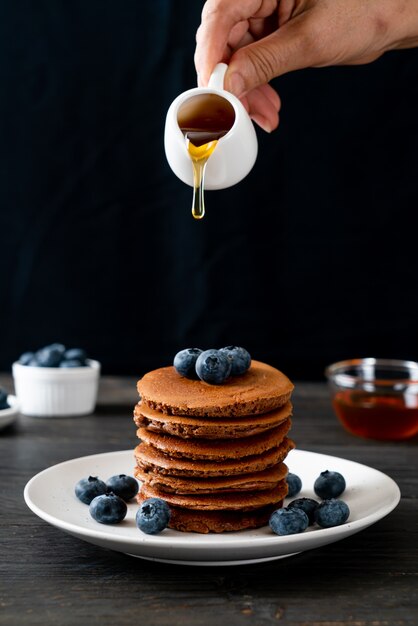 Pile de crêpes au chocolat avec myrtilles et miel sur assiette