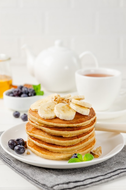 Une pile de crêpes à l'avoine et aux bananes avec des tranches de bananes fraîches, de noix et de miel