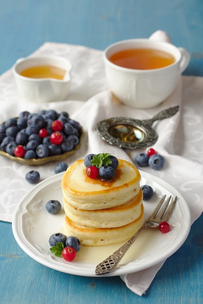 Pile de crêpes avec des baies fraîches et du miel