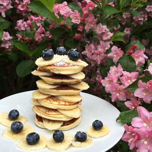 Photo une pile de crêpes avec de la banane et des bleuets.