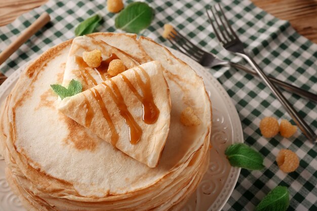 Pile de crêpes fines servies avec framboise jaune et miel