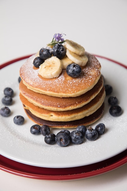 Photo pile de crêpes avec garniture de banane et de myrtilles et nourriture de petit-déjeuner au miel d'abeille