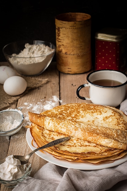 Pile de crêpes et ingrédients pour cuisiner sur une table