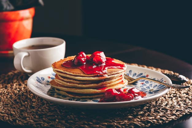 Pile de crêpes avec marmelade de baies de cornouiller sur plaque blanche ornée