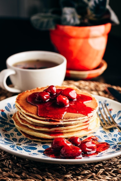 Pile de crêpes avec marmelade de baies de cornouiller sur plaque blanche ornée