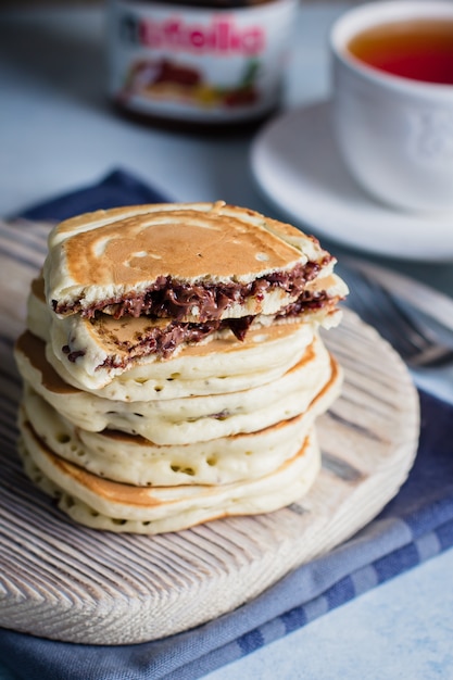 Pile de crêpes de nutella au chocolat farcies sur une planche de bois sur la table. Concept de petit déjeuner américain