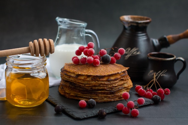 Pile de crêpes russes traditionnelles avec du miel sur fond noir avec des crêpes fines russes maison cuisine nationale russe