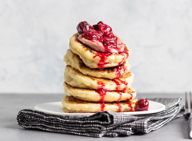 Pile de crêpes à la sauce aux cerises et au chocolat sur une assiette blanche. Petit déjeuner.