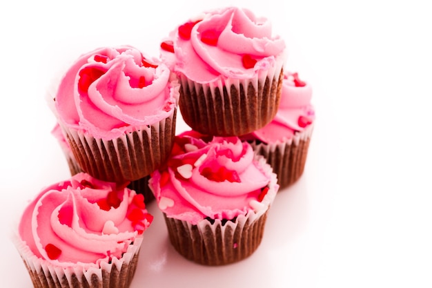 Pile de cupcakes roses avec bague de fiançailles sur le dessus.
