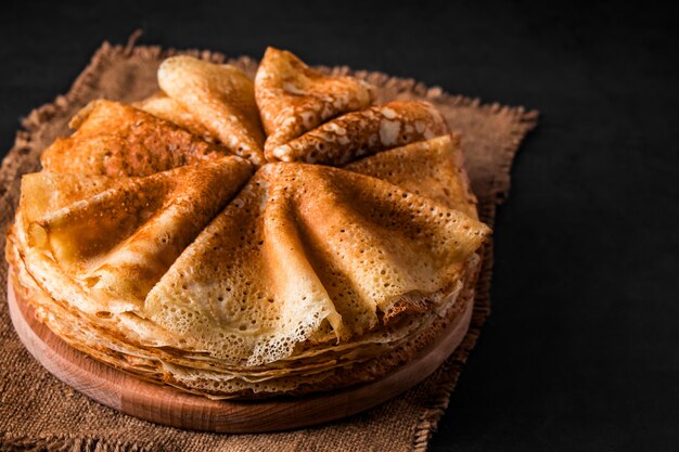 Une Pile De Délicieuses Crêpes Sur Fond Noir. Nourriture Pour Les Vacances Maslenitsa. Place Pour Votre Texte.