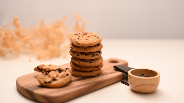 Une pile de délicieux biscuits aux pépites de chocolat sur un plateau en bois avec du sirop de chocolat dans un petit bol en bois