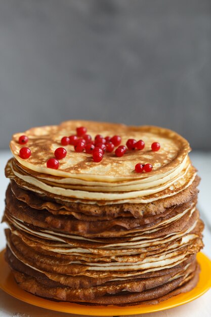 Pile élevée de crêpes minces russes classiques avec des baies de cassis. Style rustique. Traditionnel pour la semaine des crêpes russes (Maslenitsa)