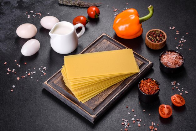 Pile de feuilles de lasagne sur fond de béton foncé Ingrédients pour lasagne