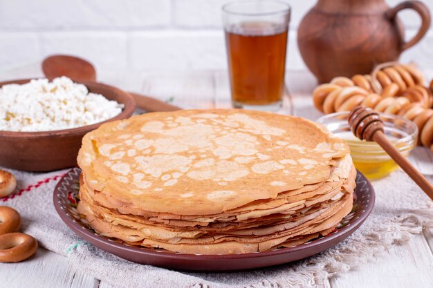 Pile de fines crêpes dans une assiette sur une table en bois blanc