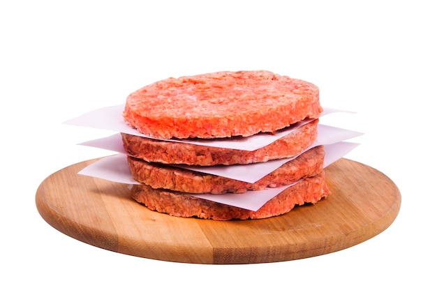 Pile de hamburgers congelés séparés avec du papier d'aluminium sur planche de bois isolé sur fond blanc