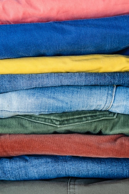 Pile de jeans et de pantalons soigneusement pliés aux couleurs vives