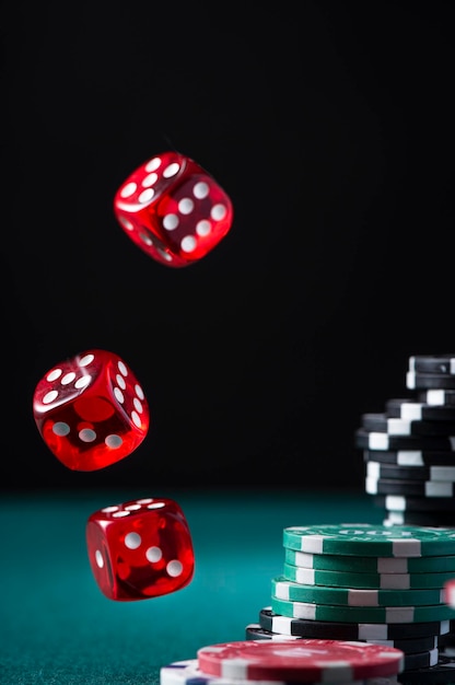 Pile de jetons de casino et dés volants sur table de poker verte