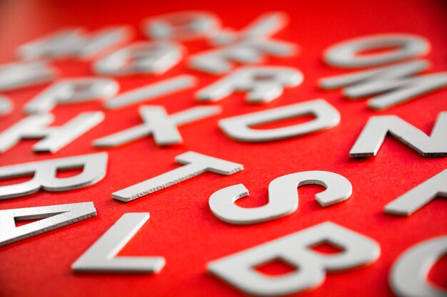 Pile de lettres solides mélangées vue rapprochée photo. Concept d'éducation sur fond rouge.