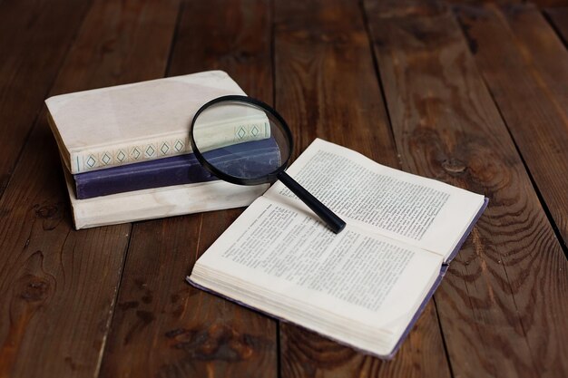 Pile de livres anciens avec loupe sur table en bois