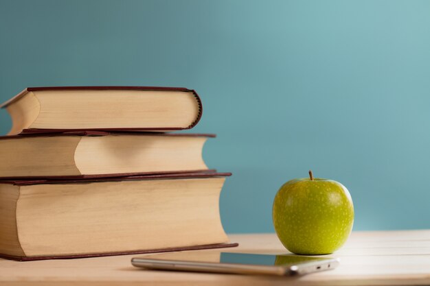 pile de livres anciens avec pomme verte et téléphone portable