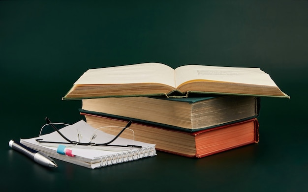 Une pile de livres avec un cahier et un stylo