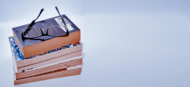 Pile de livres disposés pile sur fond blanc avec des lunettes sur le dessus de l'espace de copie vue grand angle