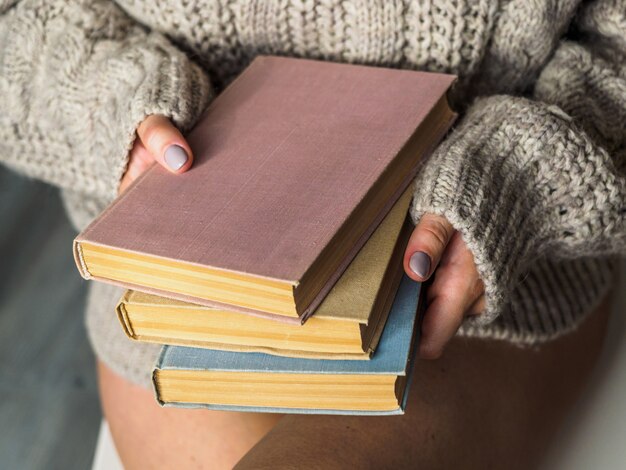 Une pile de livres entre les mains de la femme