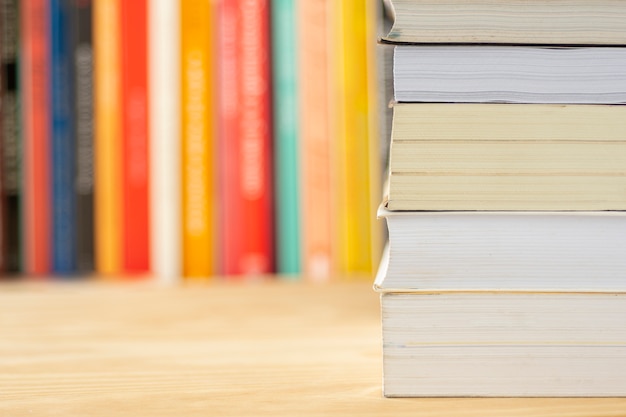 Pile de livres en face de livres flous sur une table en bois